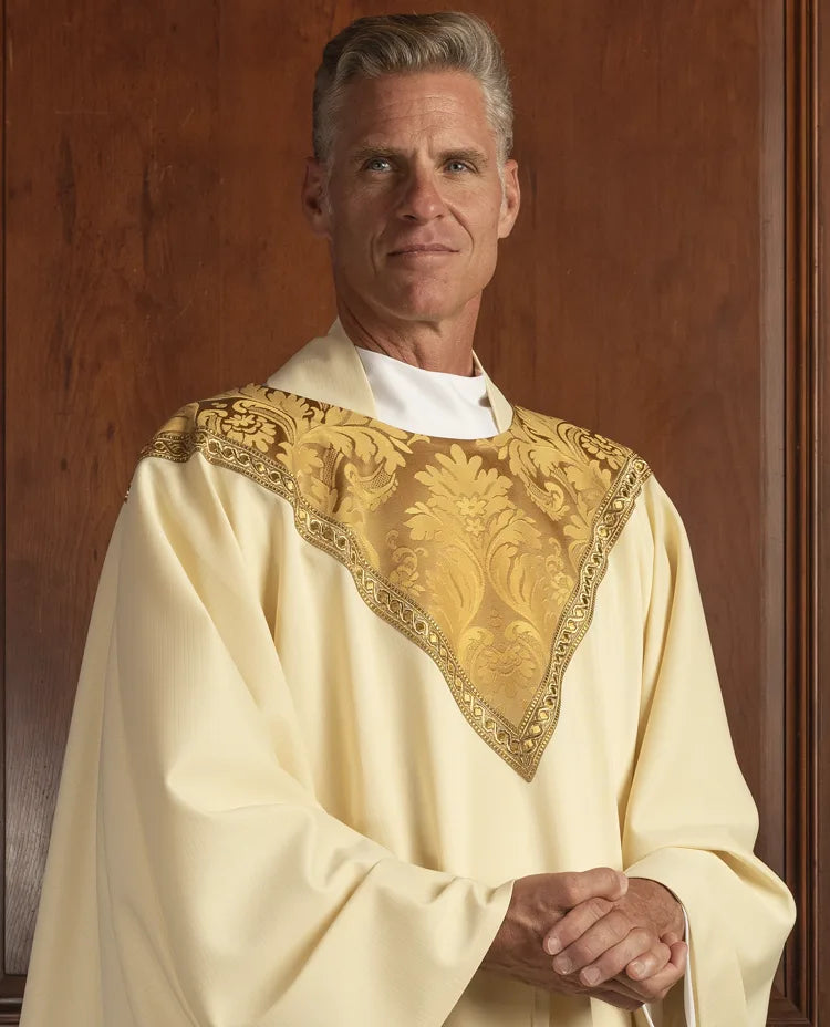 Man wearing a white robe with gold embroidery against a wooden background