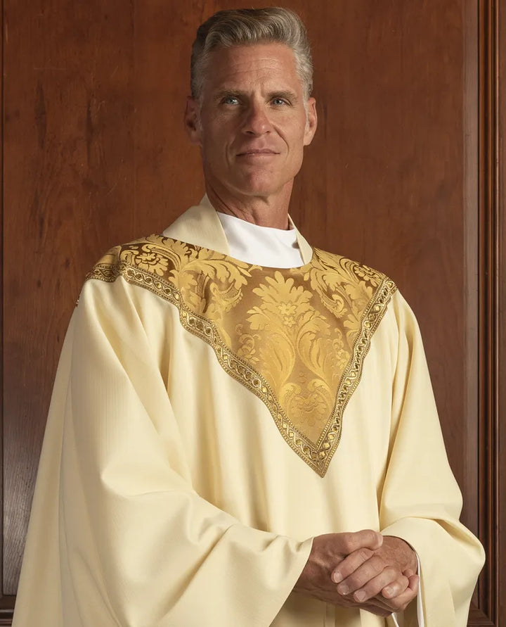 Man wearing a white robe with gold embroidery against a wooden background