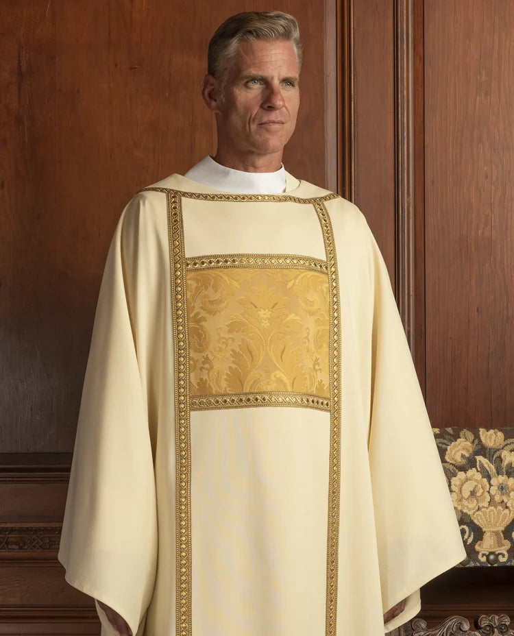 Man wearing a white liturgical vestment with gold embroidery against a wooden background
