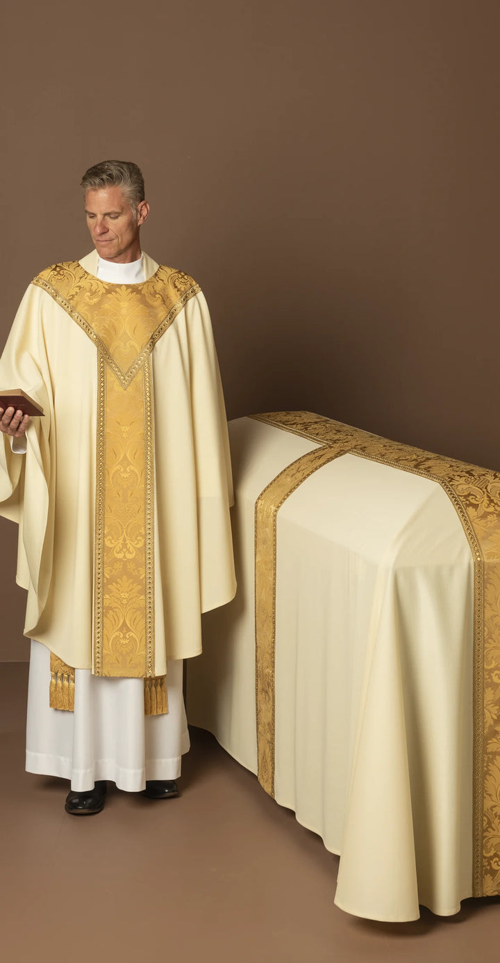 Priest in liturgical vestments standing next to an altar covered with a cloth.